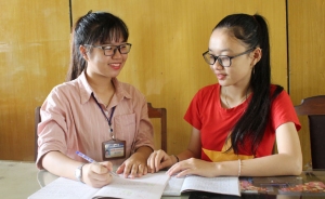 Nguyễn Thị Phương Đài (trái) trao đổi bài với một bạn học trong lớp.