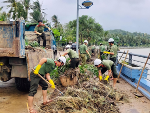 Đoàn viên thanh niên Công an tỉnh giúp dân thu gom rác, dọn bùn tại TX Sông Cầu sau cơn bão số 12.