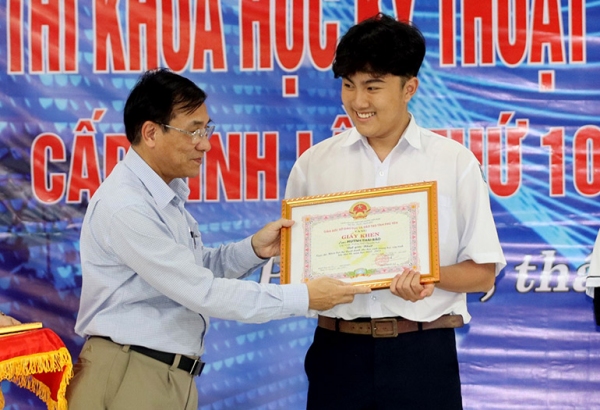 Giám đốc Sở GD-ĐT Trần Khắc Lễ trao giải nhất cho em Huỳnh Thái Bảo. Ảnh: HIẾU TRUNG