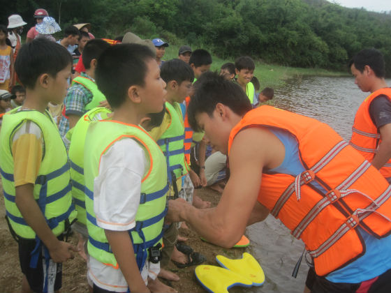 Các em học sinh thực hành mặc áo phao đúng cách trước khi tập bơi