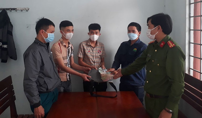Anh Lê Văn Chung (thứ 2 từ phải sang) bàn giao số tiền nhặt được cho người mất.