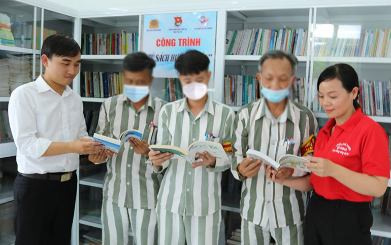 Trung úy Lê Tuấn Thành (bìa trái) hướng dẫn phạm nhân Trại giam Xuân Phước phương pháp đọc sách đúng cách. Ảnh: HÀ MY